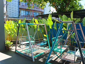 Two swings in outdoor of Sekolah Karya Anak Bangsa and background of green plants. 
