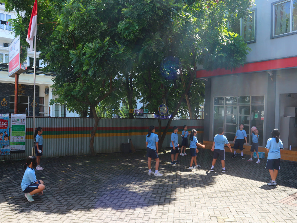 Outdoor of school showing students doing exercises using physical education uniform.