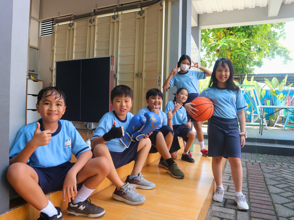 Primary (SD) students in Sekolah Karya Anak Bangsa Manado sitting down using olarhraga uniform.