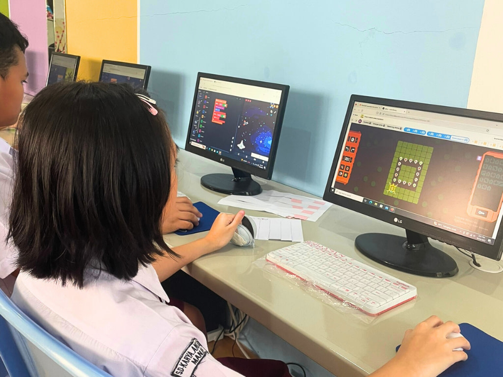 Primary student (SD) from Sekolah Karya Anak Bangsa Manado studying coding in front of a computer in class.