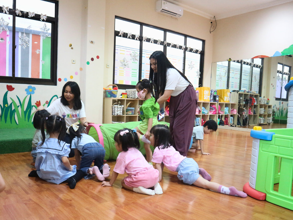 two teachers guiding a group of Kiddy School students during morning song activity time.