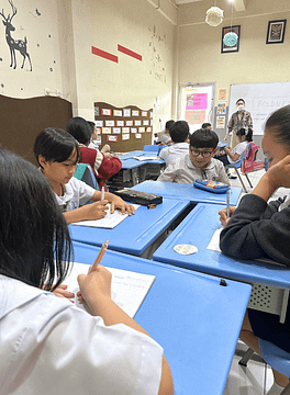 Primary.1 A group of primary students studying in a class with a collaborative table setting.
