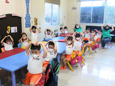 kindergarten.7 A group of kindergarten students with teacher posing into the camera in Kiddy School classroom.