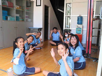 skab.2 Primary children sitting in a circle smiling and laughing.