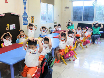 kindergarten.7 A group of kindergarten students with teacher posing into the camera in Kiddy School classroom.