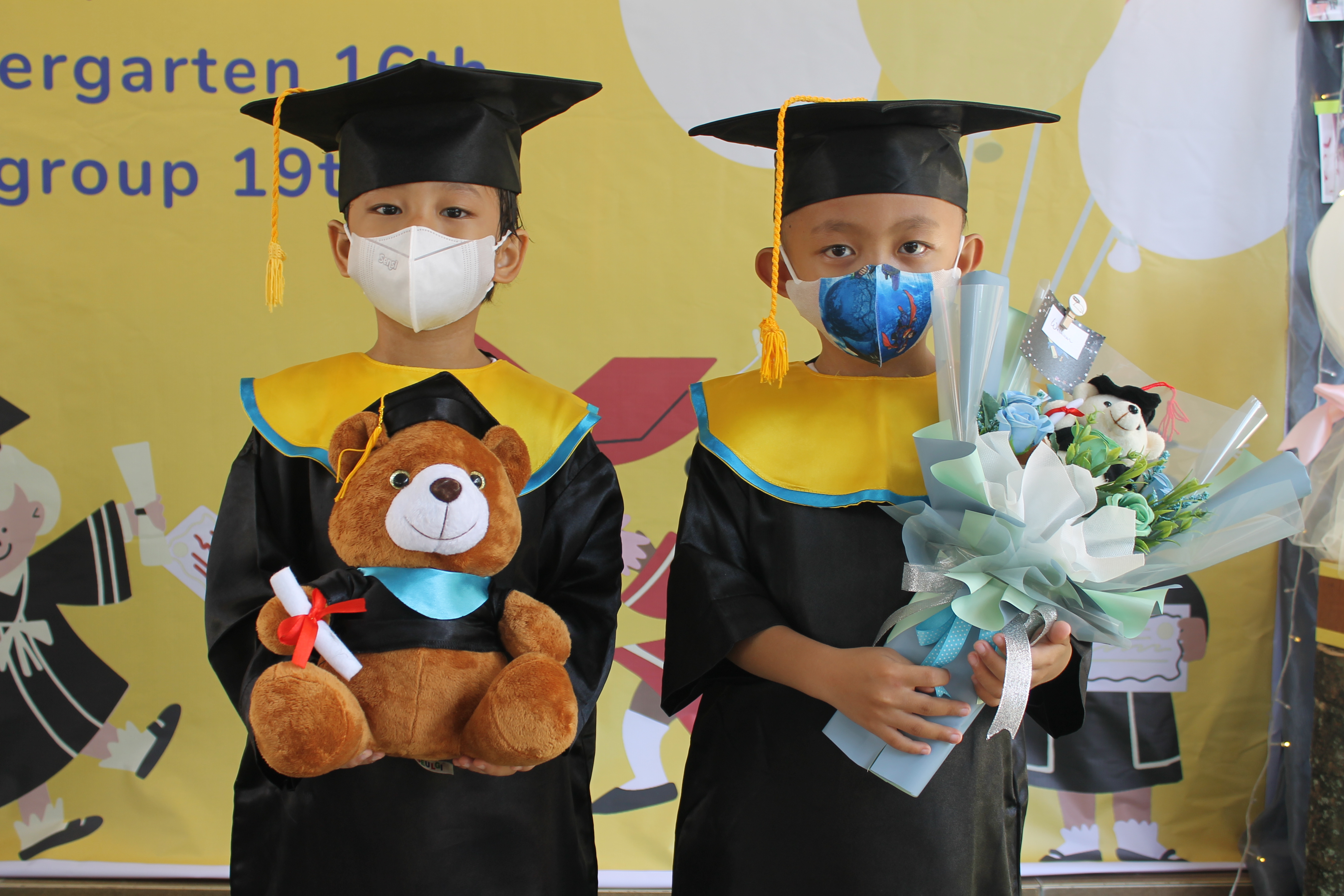 kindergarten.4 Two young students graduating and posing with their graduation coat.
