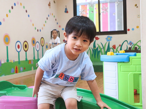 playgroup.10 A young playgroup student using a blue uniform shirt, smiling at the camera.