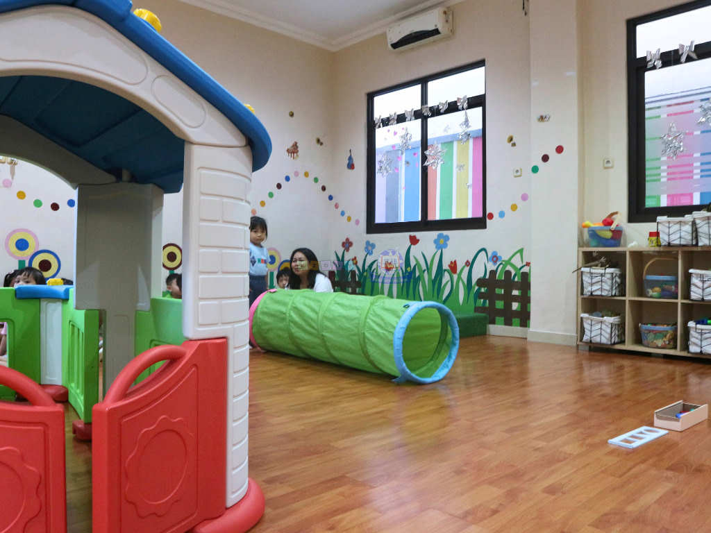 Indoor of Kiddy School Manado where students can play in clean and comfortable space with wooden flooring and AC.