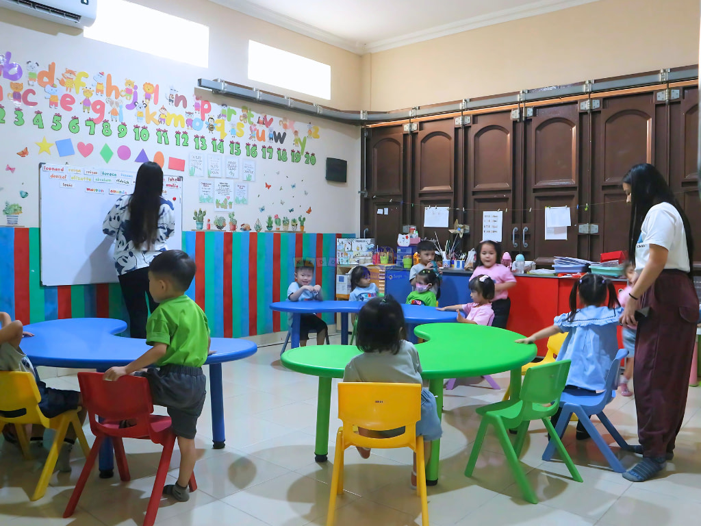 Playrgoup class in Kiddy School Manado where students are sitting and listening to a teacher at the whiteboard area.