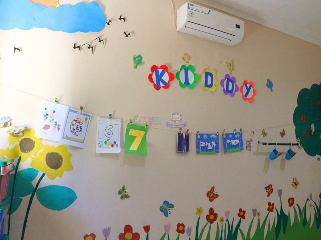 A wall filled with children's creative drawings, arts, and crafts in Kiddy School